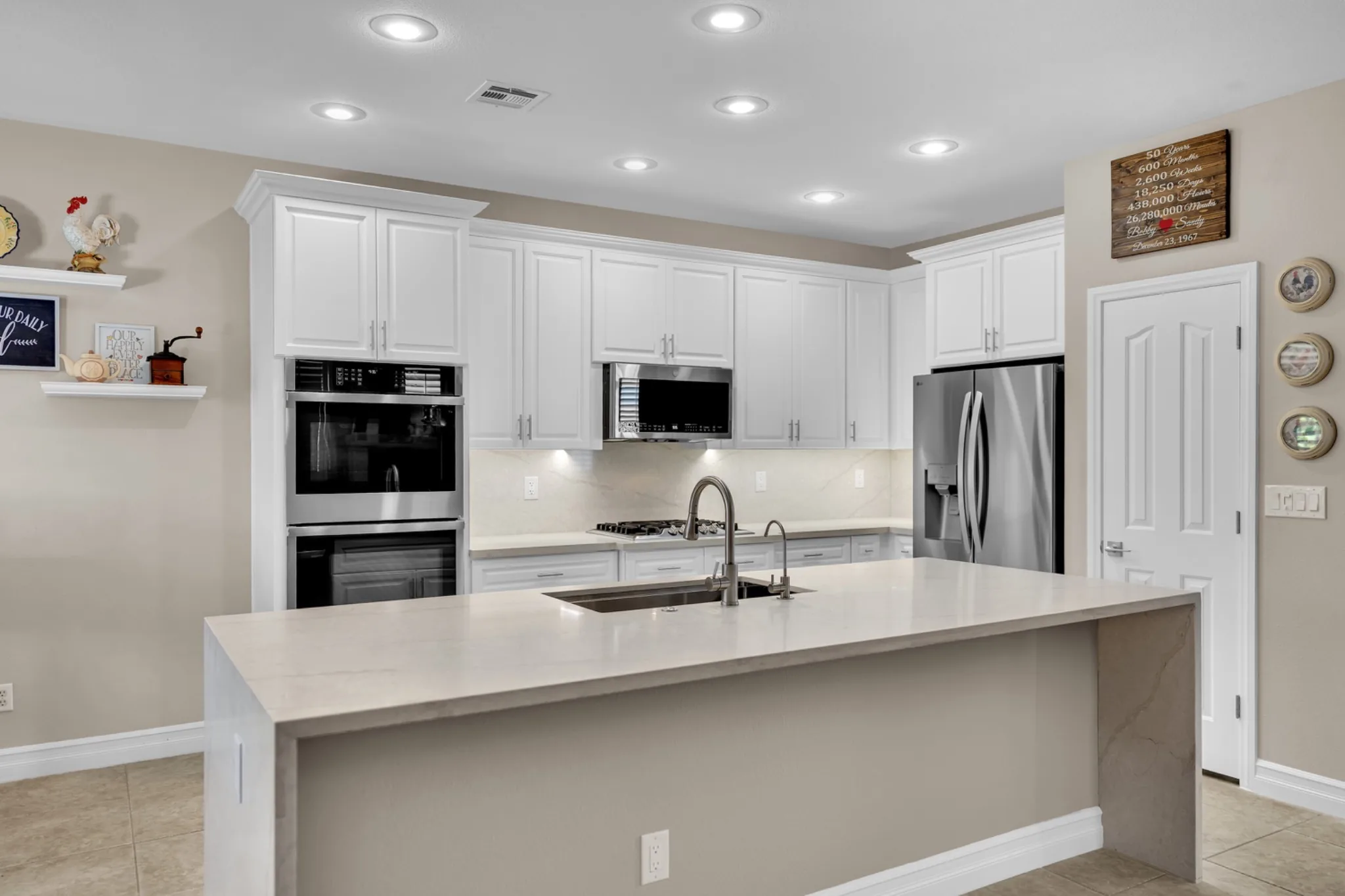 Prefab kitchen remodel with white raised-panel cabinets, leathered quartz countertops, enlarged single-level island, and stainless appliances